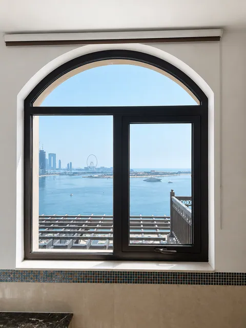 Arched black-framed window with sea view toward Ain Dubai, Fairmont Palm apartment