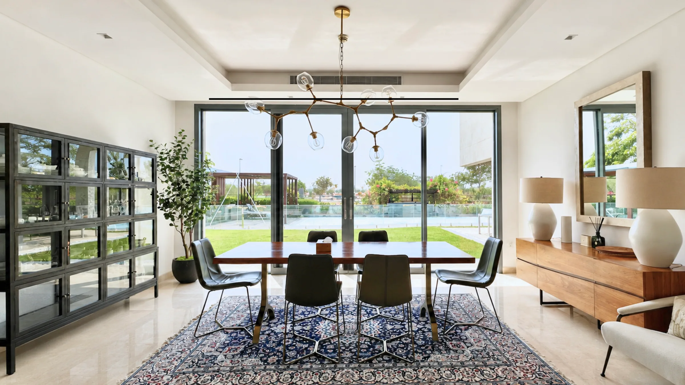 Dining room with full-height sliding doors onto the garden, Yas Acres villa